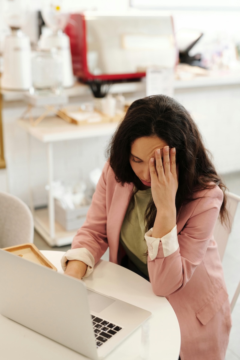 **Alt text:** "A woman stressed at her computer, overwhelmed by financial tasks, reflecting the challenges high-net-worth individuals face in managing complex financial decisions and avoiding costly mistakes. The image illustrates the emotional toll that small errors in financial execution, such as poor tax planning or estate management, can take, underscoring the importance of proper financial oversight."
